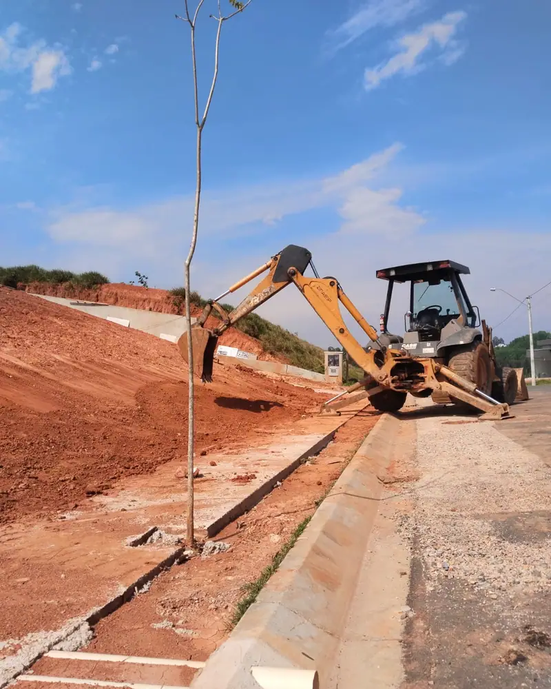 Retroescavadeira trabalhando em uma encosta, ao lado de uma sarjeta recém-feita